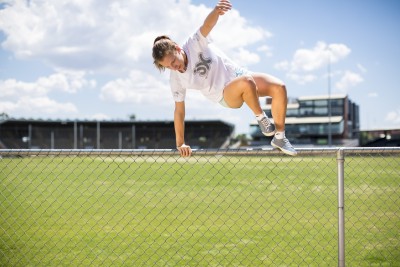 Young person leaping over fence